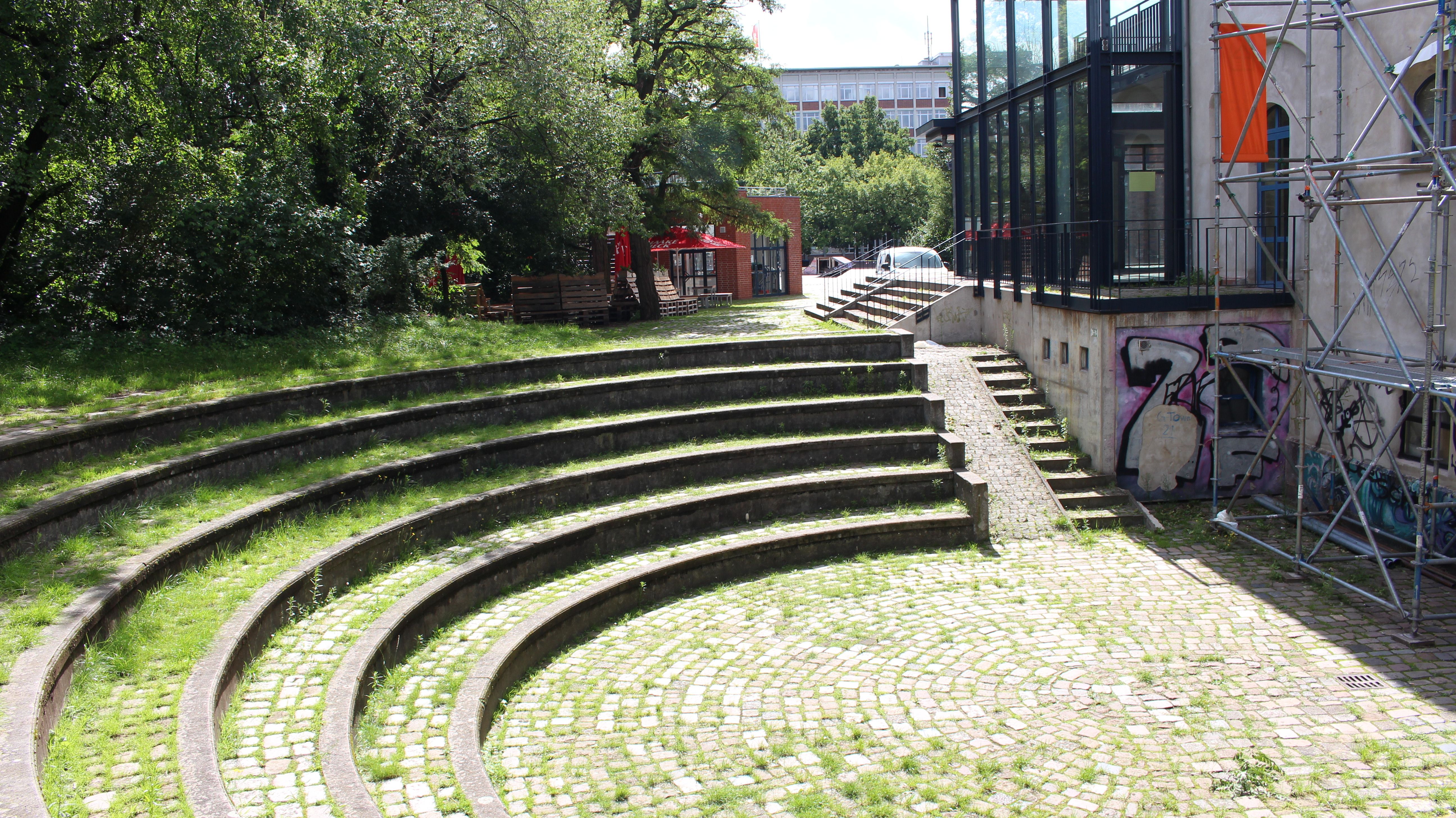 Die Arena ist wie ein Amphitheater angelegt. Die Steinstufen dienen als Tribüne rund um die niedrig gelegenere Bühnenfläche.