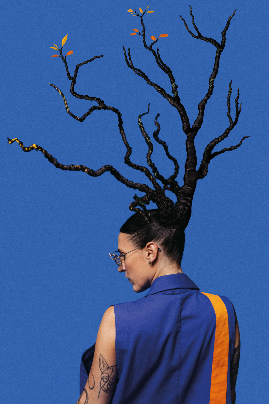 Die Künstlerin Mine steht mit dem Rücken zur Betrachter:in und aus ihren Haaren wächst ein Baum.