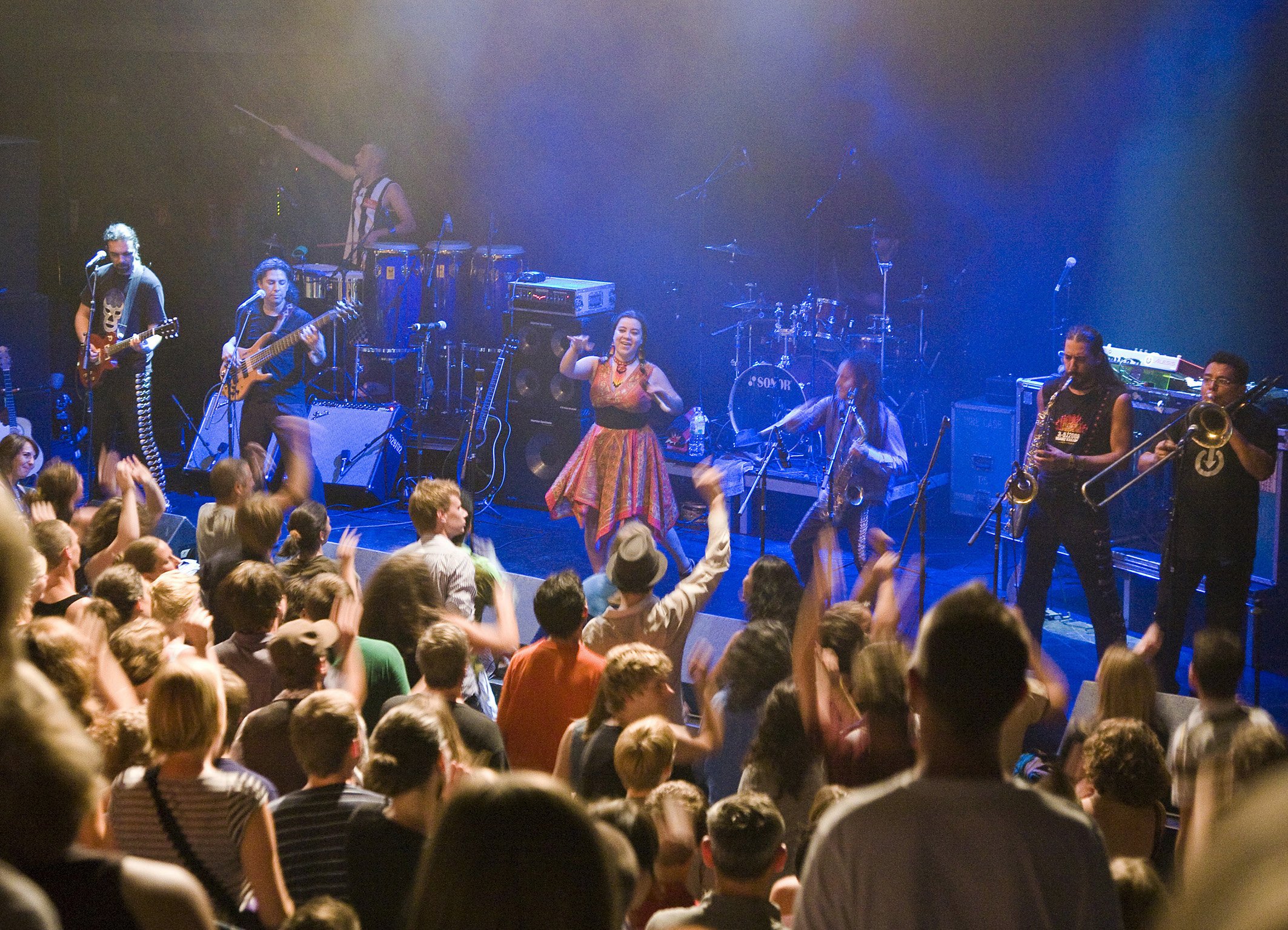 Die Band Los de Abajo spielen auf der Bühne der Kesselhalle vor einem tanzenden Publikum.