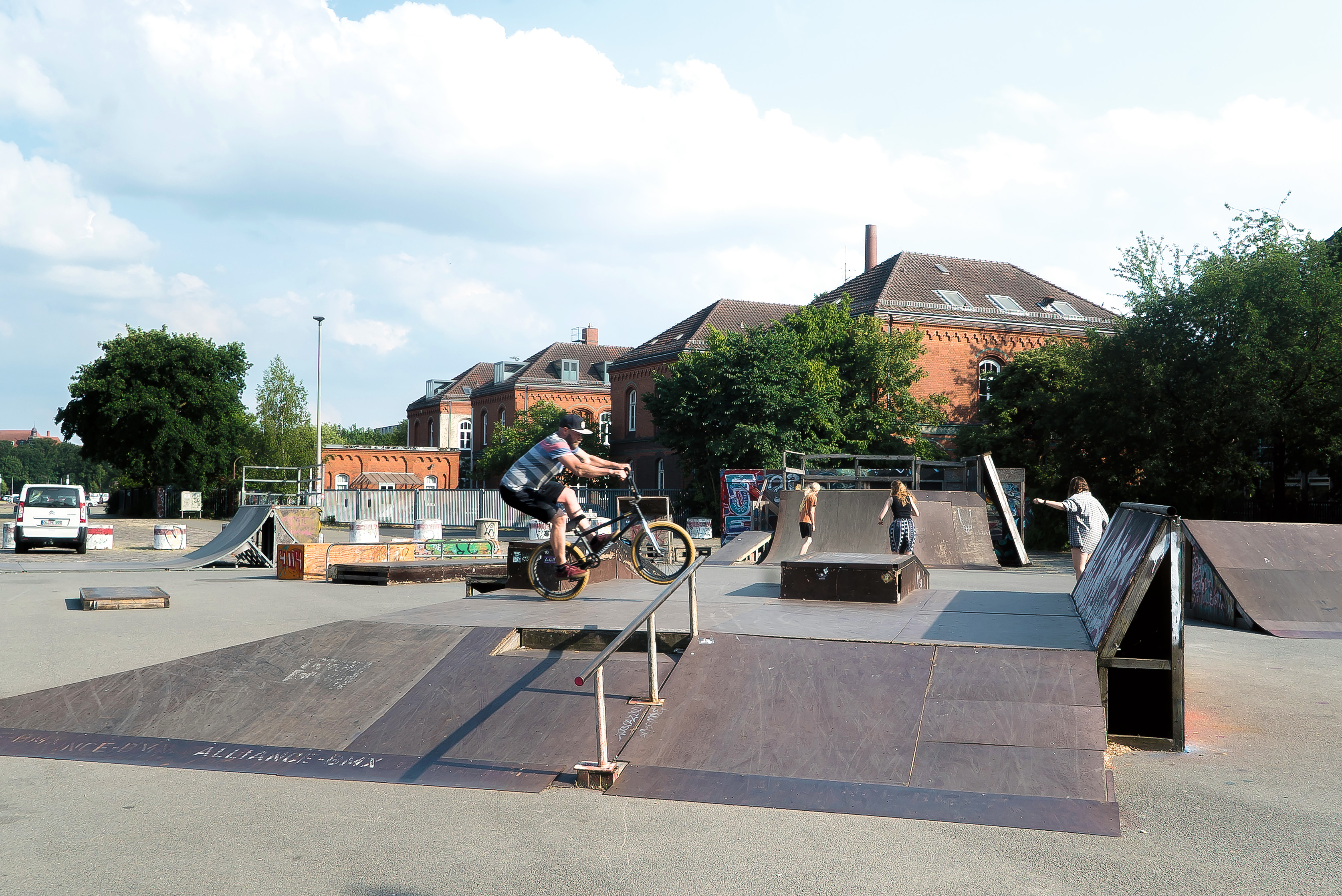 Auf dem Skaterplatz vor dem Kulturzentrum Schlachthhof fährt ein BMX-Fahrer über eine Rampe. Im Hintergrund fahren drei Skaterinnen.